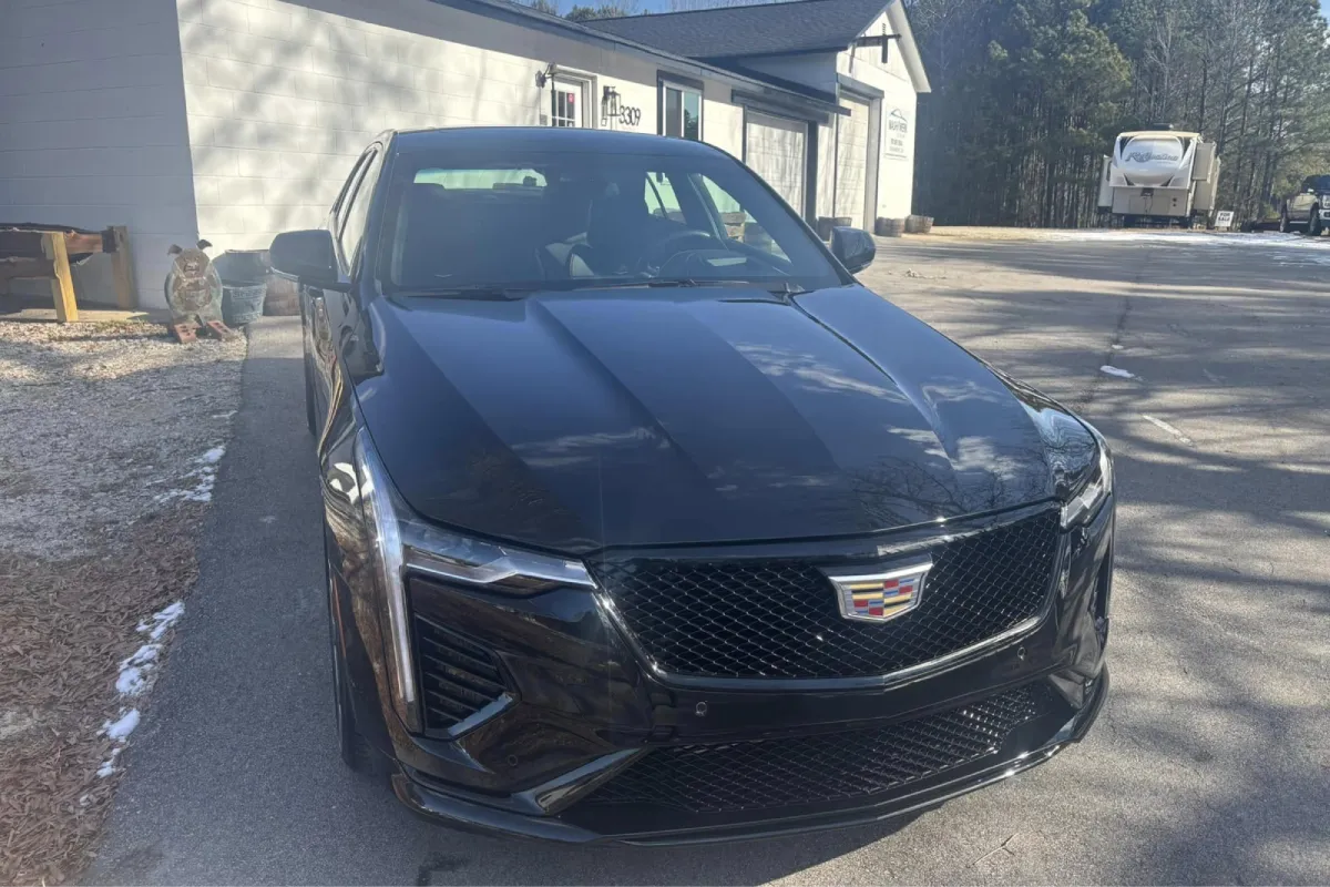 Black car parked outside detailing shop with glossy finish