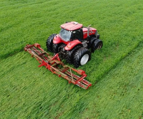 Red farm tractor applying agricultural coating protection in crop field.