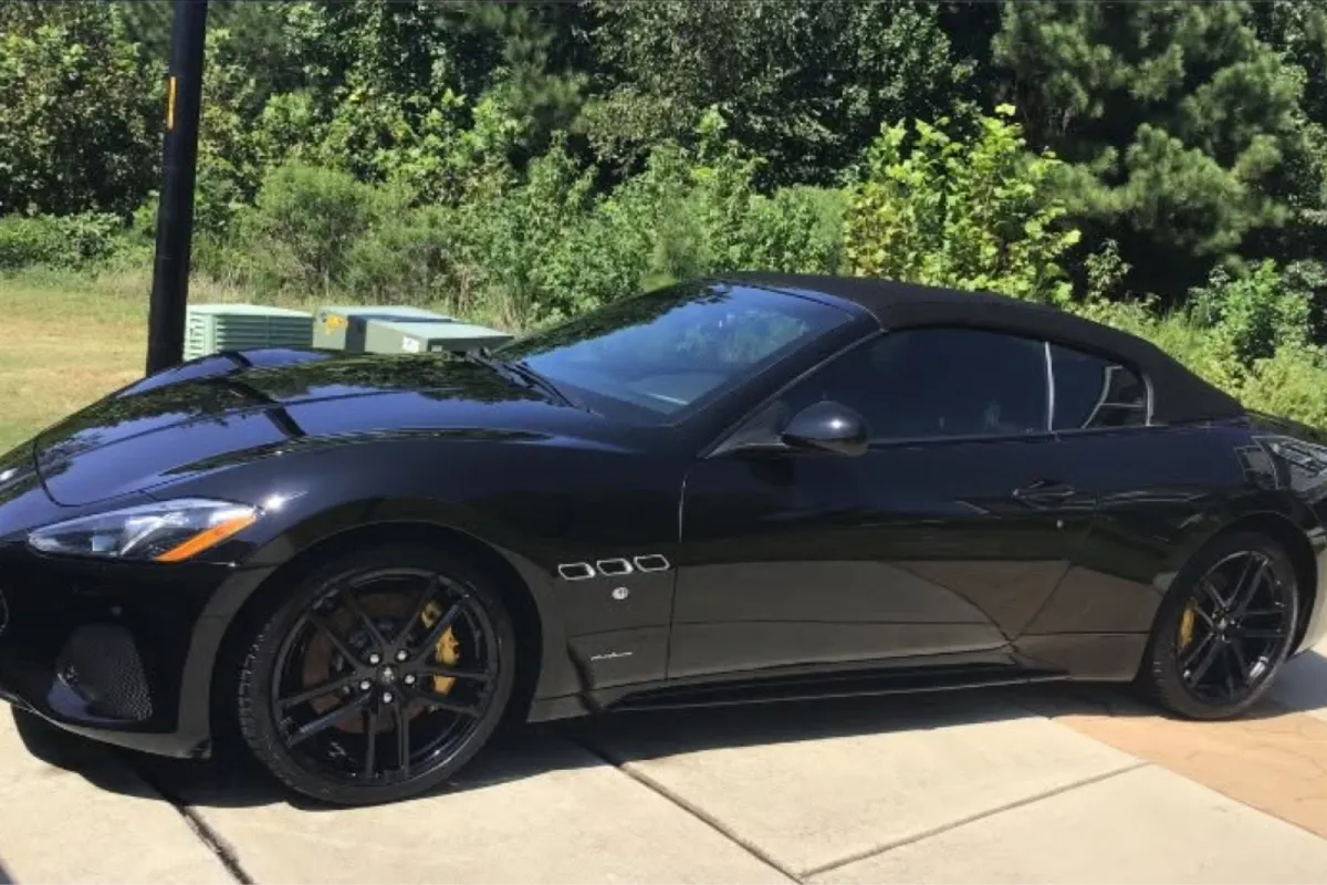 Black convertible sports car with glossy finish after paint correction outdoors.