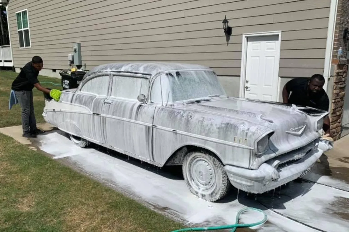 Classic car being washed with foam during exterior detailing.